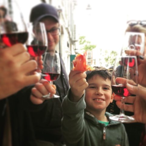 a group of people holding a glass of wine and a children toasting with a slice of ham