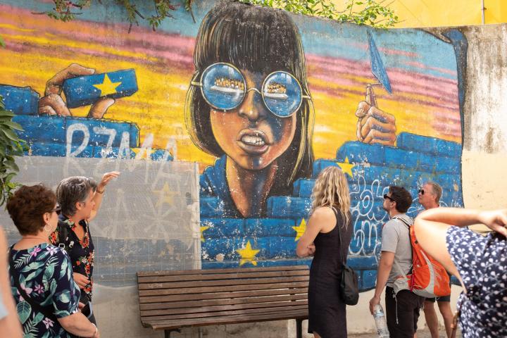 a group of people standing next to a graffiti covered wall