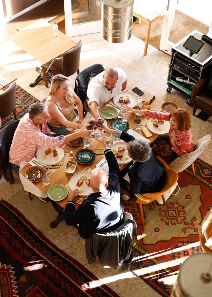 group people around a table doing cheers