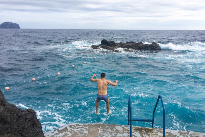 a person standing on a rocky beach next to the ocean
