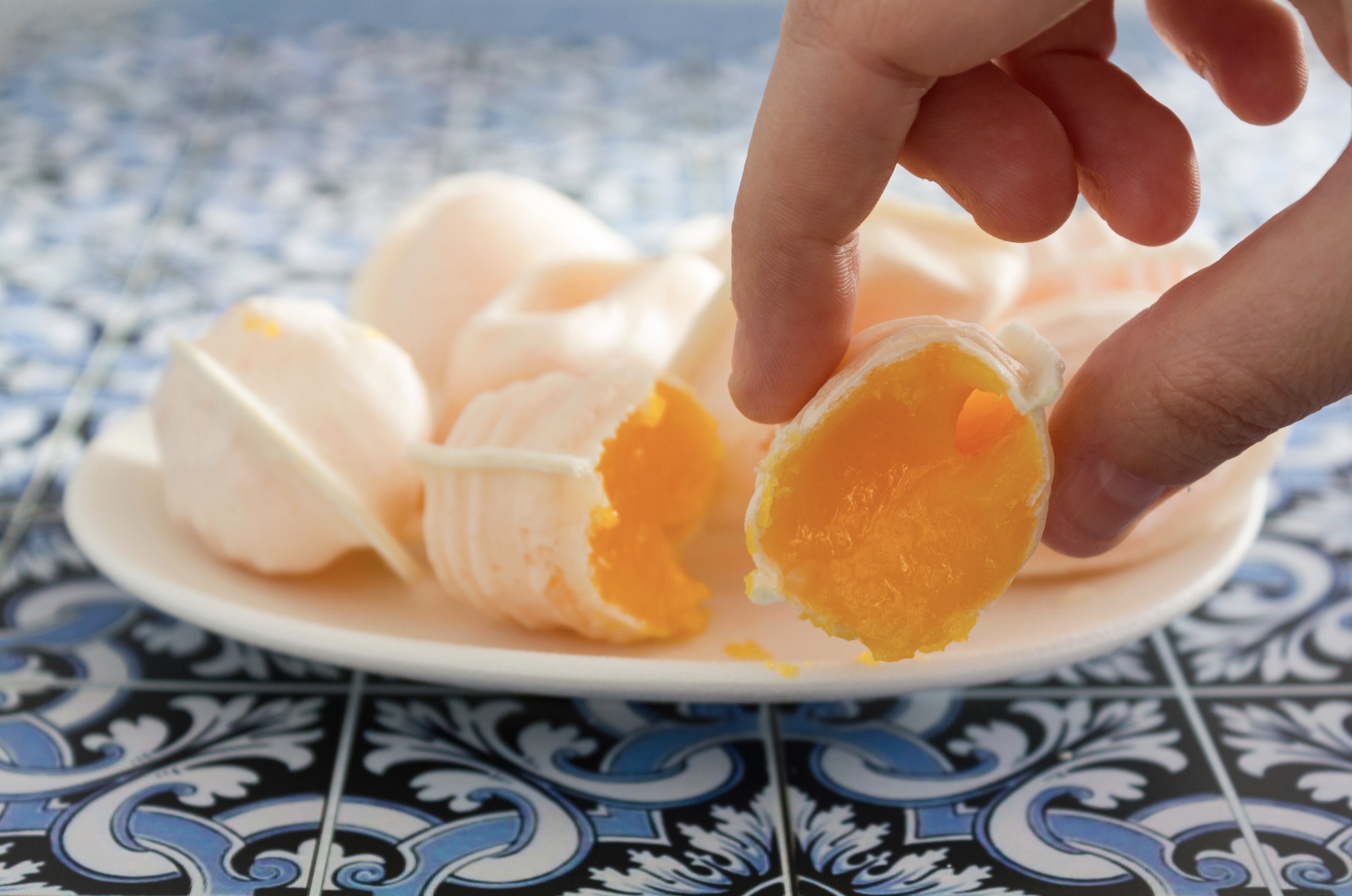 a close up of someone grabbing a ovos moles sweet from a plate