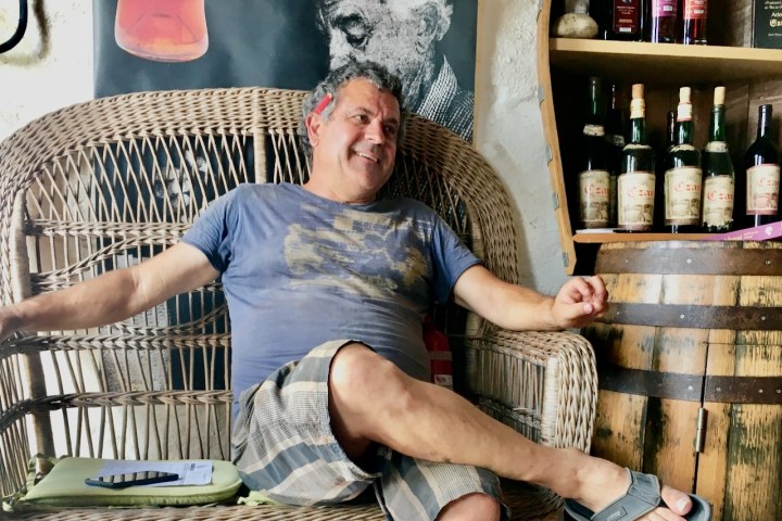 a man standing next to a bottle of wine
