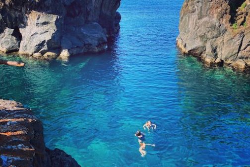 a group of people in a rocky area next to a body of water