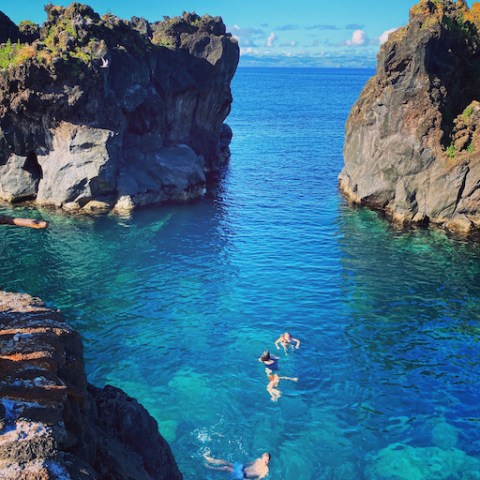 a group of people in a rocky area next to a body of water
