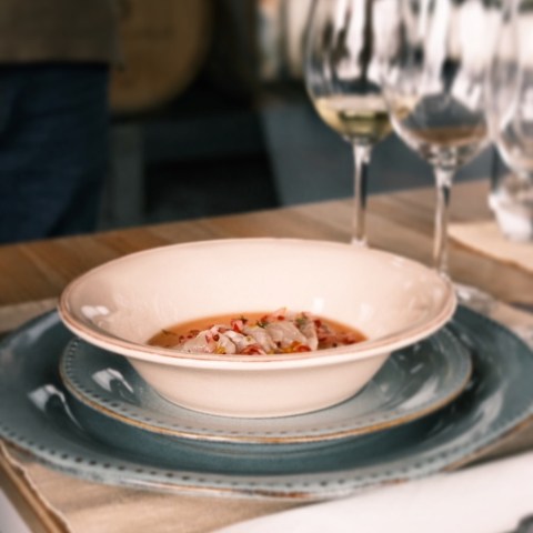 Bowl of soup on a set table with wine glasses and cutlery.