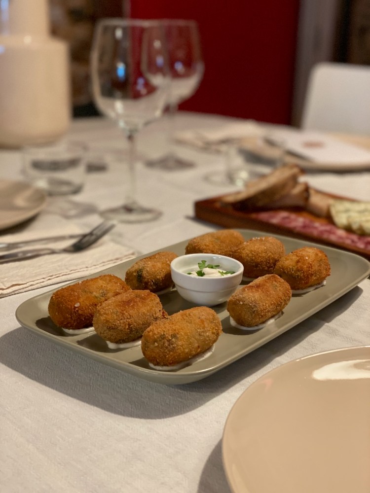 Plate of croquettes with a small bowl of dipping sauce on a set dining table.
