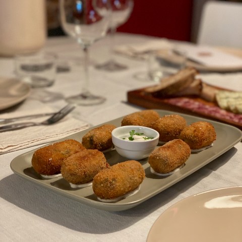 Plate of croquettes with a small bowl of dipping sauce on a set dining table.