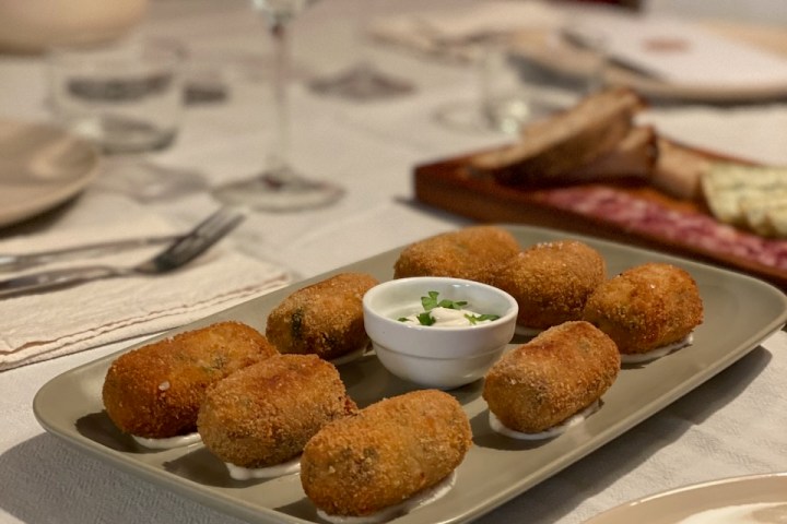 Plate of croquettes with a small bowl of dipping sauce on a set dining table.
