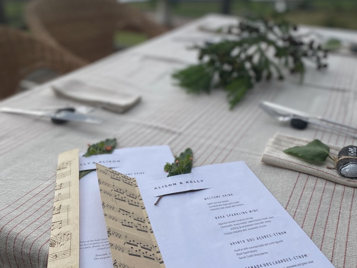 Menus on a striped tablecloth with ocean view and greenery decoration.