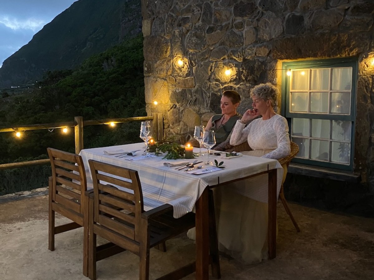 Two people dining at an outdoor table with a mountain view at dusk.