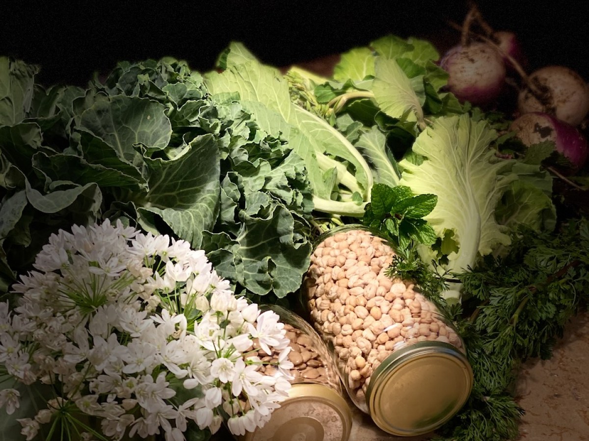 Jars of nuts, leafy greens, white flowers, and turnips on a surface.