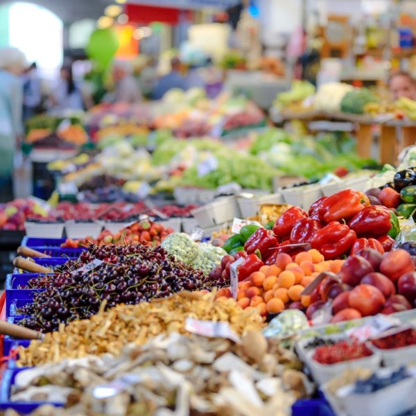 Market stand with fresh fruits and vegetables, including peppers, cherries, and greens.