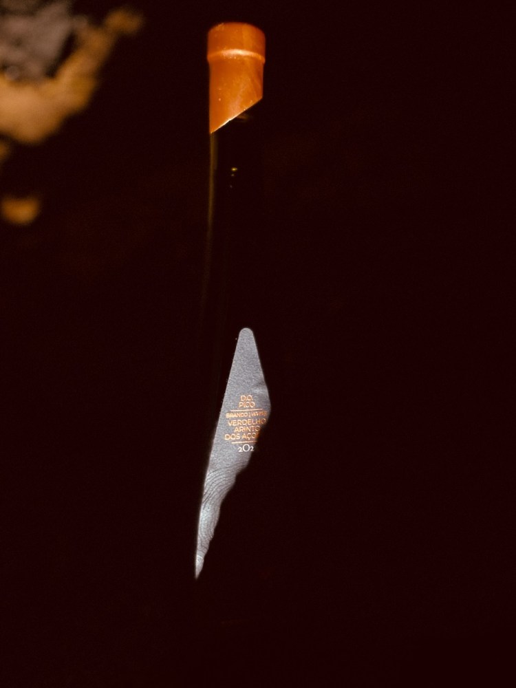 Dark bottle with orange wax seal, partially lit against dark background.