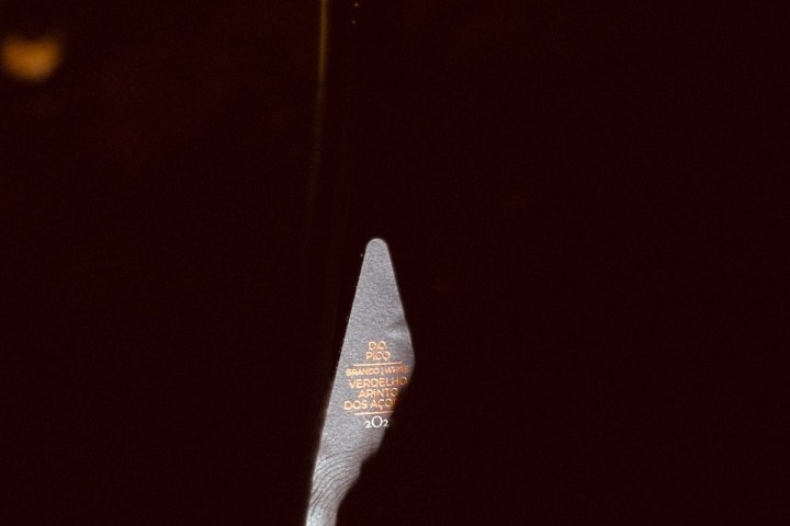 Dark bottle with orange wax seal, partially lit against dark background.
