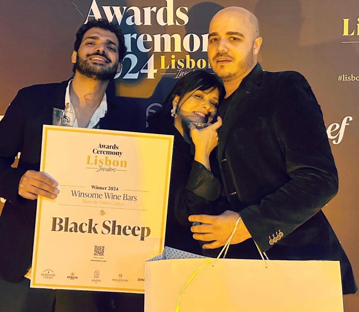 Three people smiling, holding a 'Winsome Wine Bars' award at an event in Lisbon.