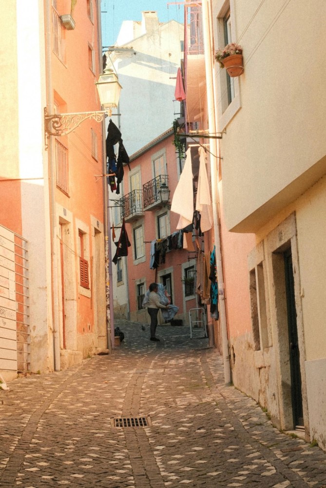 Narrow street with hanging laundry between pastel buildings.