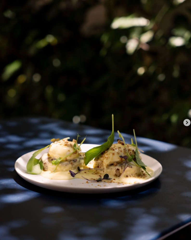 Poached eggs with greens on white plate, outdoor setting
