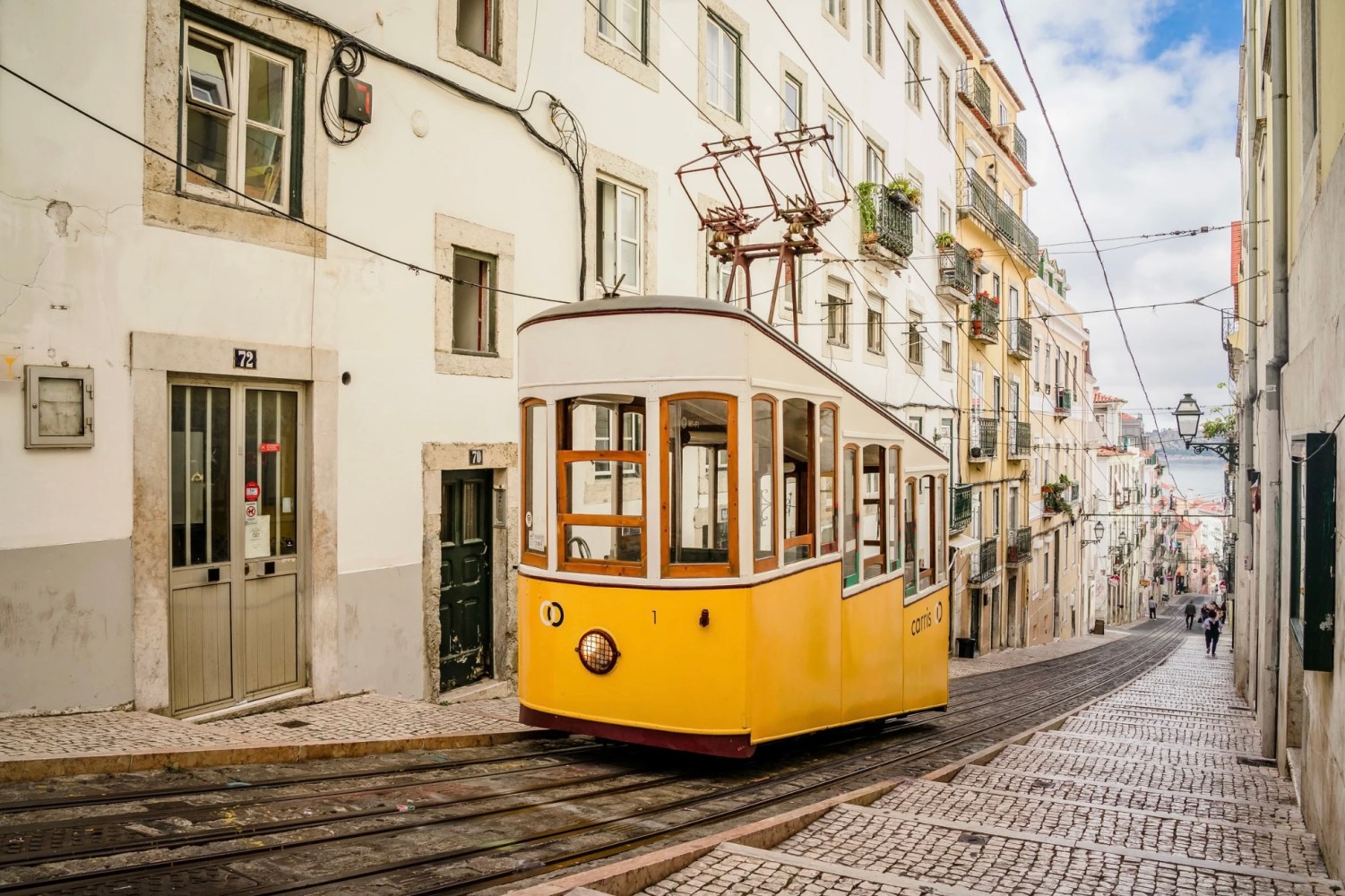Yellow tram on a steep street lined with buildings.
